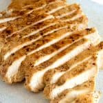 Sliced cooked chicken breast for a salad on a cutting board.