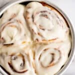 Overhead photo of a small batch of cinnamon rolls with cream cheese frosting in a baking dish.