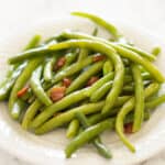 Bacon green beans on a white plate.