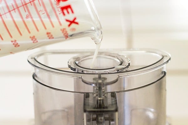 Buttermilk being poured into food processor for pie dough.