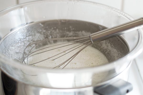 Eggs and sugar being heated over double boiler for marshmallow frosting.