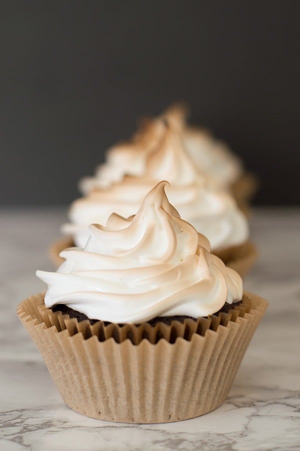 Three S'mores cupcakes on a marble counter.