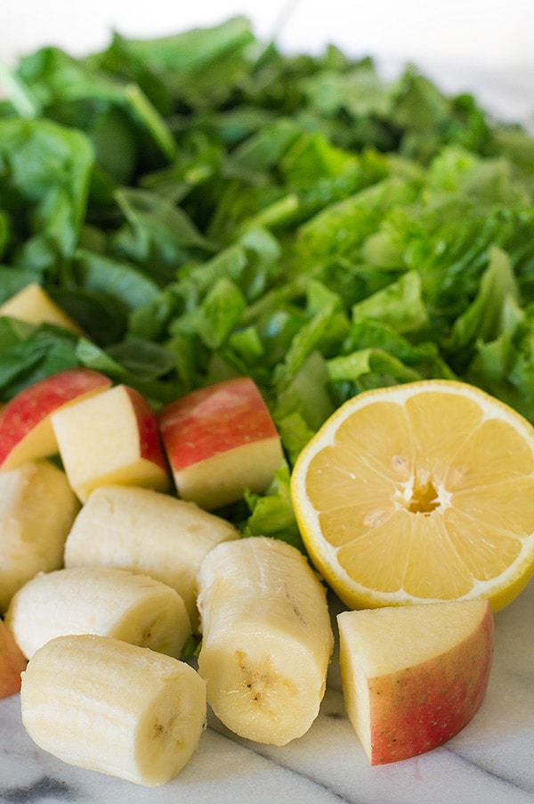Green smoothie ingredients on a marble cutting board.