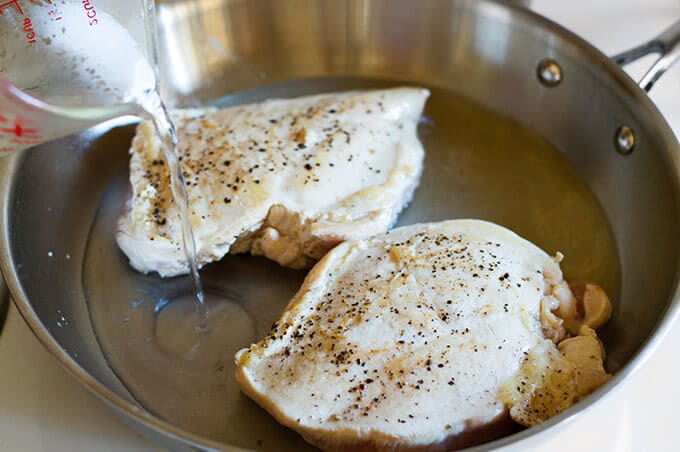 Water being added to a pan of chicken. 