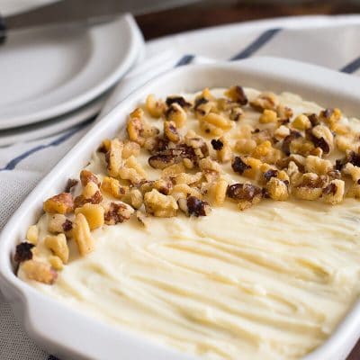 Photo of small carrot cake with cream cheese frosting in a white dish.