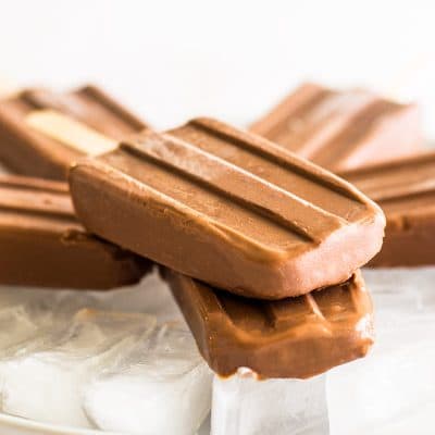 Homemade pudding pops stacked on a plate of ice.