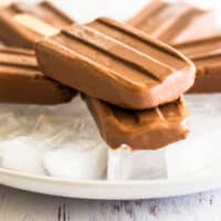 Homemade pudding pops stacked on a plate of ice.