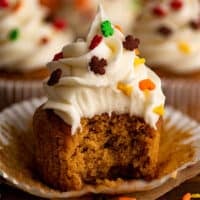Pumpkin cupcake with cream cheese frosting with a bite out of it.