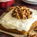 Mini pumpkin cake with cream cheese frosting with candied walnuts piled on top.