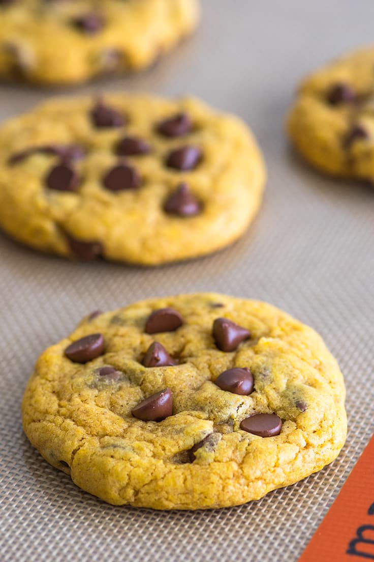 Chocolate chip pumpkin cookies on a baking mat.