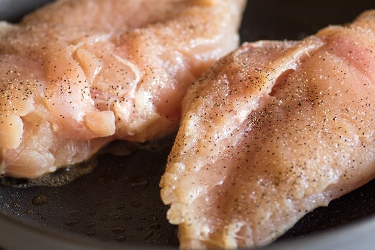 Thermometer checking the temperature of chicken breasts.