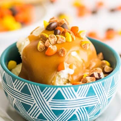 Photo of peanut butter sauce in a blue bowl with chopped up Reese's Pieces on top.