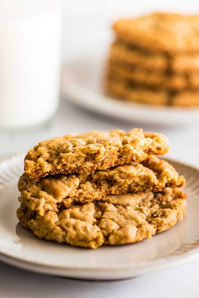 Photo of two peanut butter oatmeal cookies on a plate with a glass of milk.