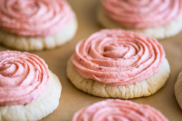 Close up photo of Lemon Cookies With Strawberry Frosting on parchment paper.
