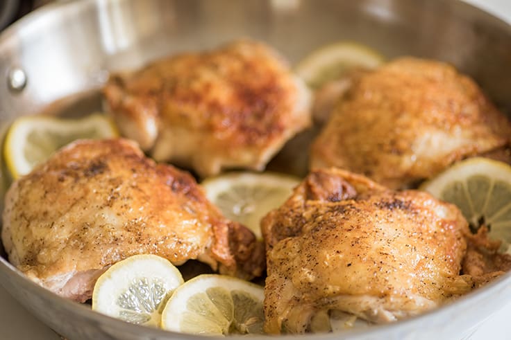 Lemon chicken thighs in skillet.