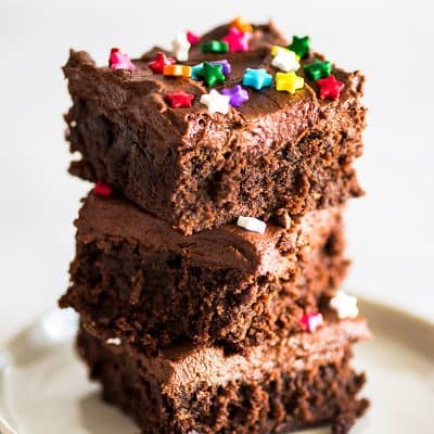 Picture of three frosted brownies stacked on a white plate.
