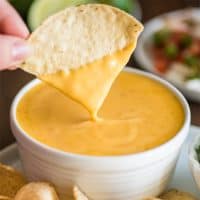 Picture of tortilla chip being dipped into homemade nacho cheese.