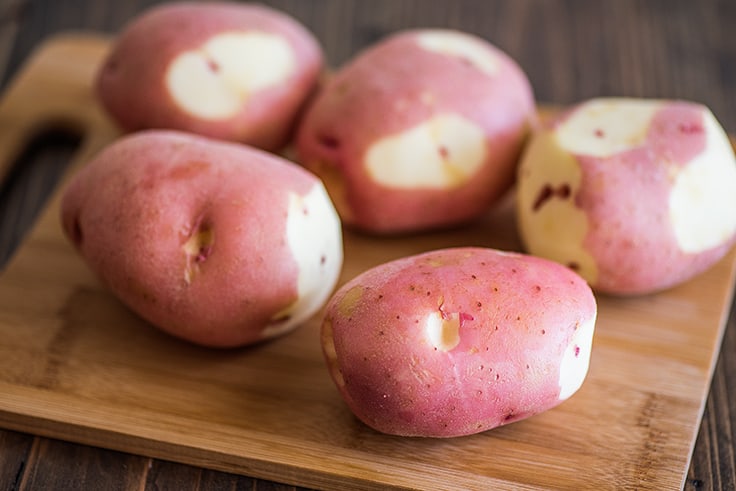 Red potatoes on a cutting board.