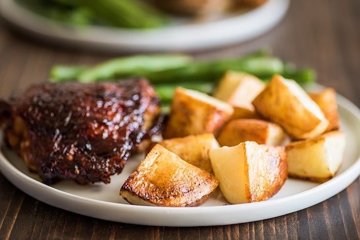 Roasted red potatoes on a white plate.