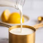 Milk being poured into a measuring up to make buttermilk substitute.