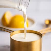 Milk being poured into a measuring up to make buttermilk substitute.