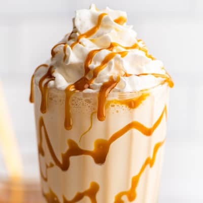 Caramel milkshake in a glass cup with whipped cream.