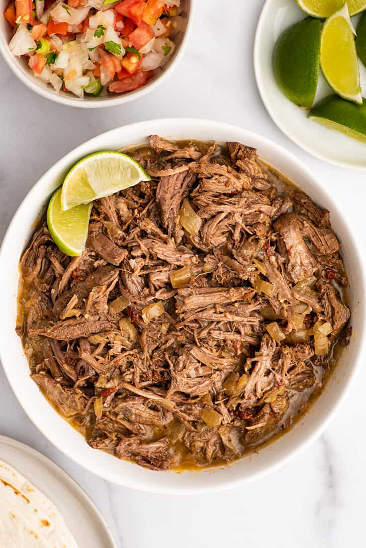 Bowl of barbacoa beef for tacos on a marble counter.