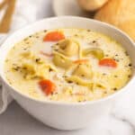 Creamy chicken tortellini soup in a white bowl.