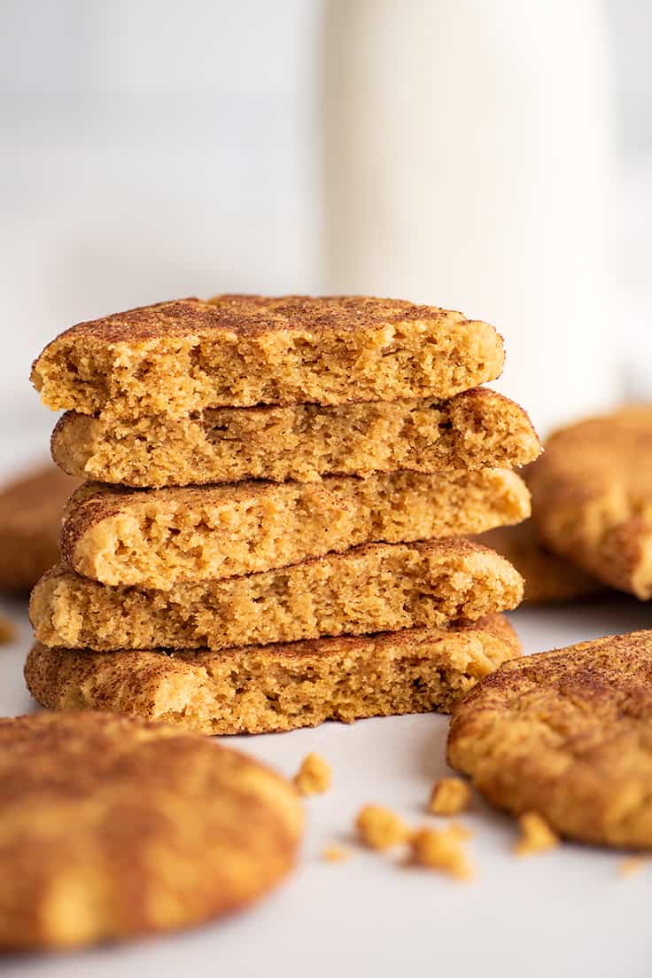 Small batch of pumpkin snickerdoodles stacked by a jar of milk.