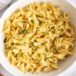 Overhead photo of buttered noodles in a white bowl.