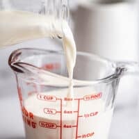 Milk being poured into a measuring cup to make half and half substitute.