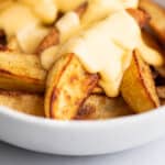 Cheese sauce being poured over fries.
