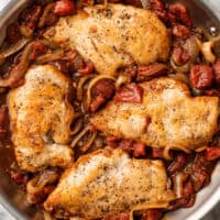 Balsamic chicken in a skillet with tomatoes and onions.