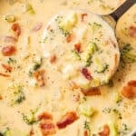 A ladle scooping out cheesy broccoli potato soup.