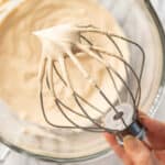Hand holding a stand mixer mix with coffee whipped cream on it.