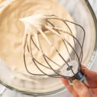 Hand holding a stand mixer mix with coffee whipped cream on it.