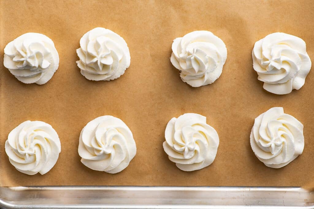 Dollops of whipped cream on a baking sheet for freezing.