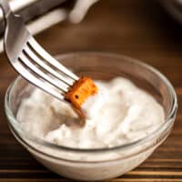 Sweet potato being dipped in greek yogurt aioli.