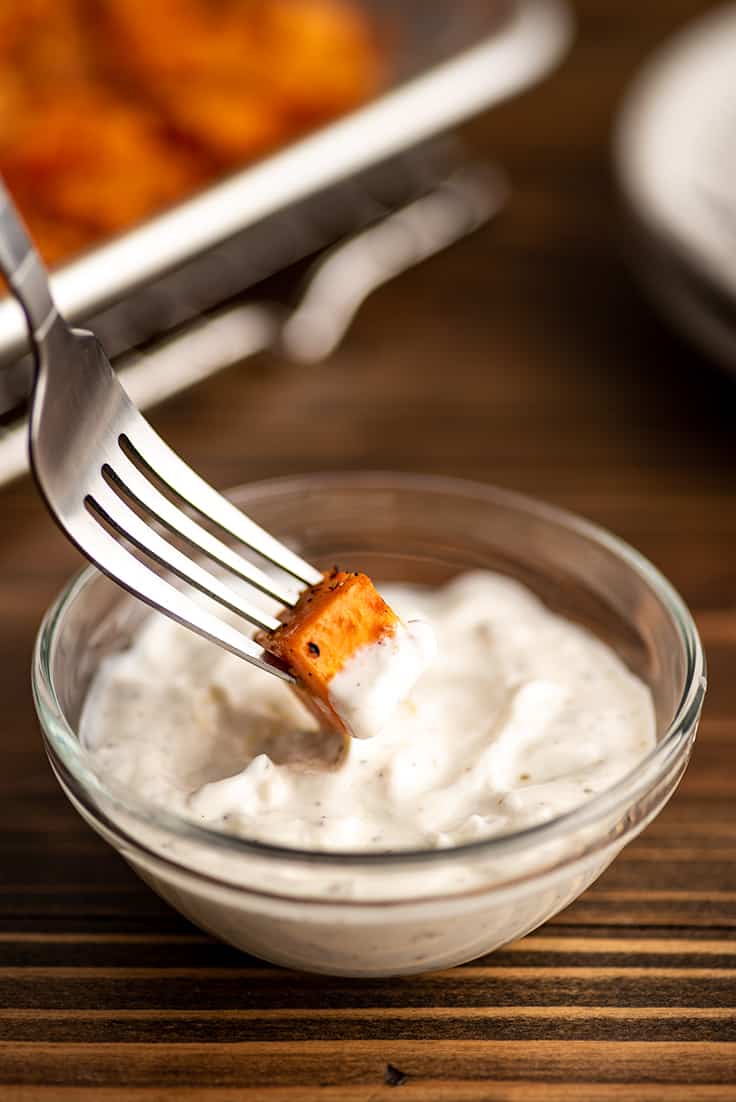 Sweet potato being dipped in greek yogurt aioli.