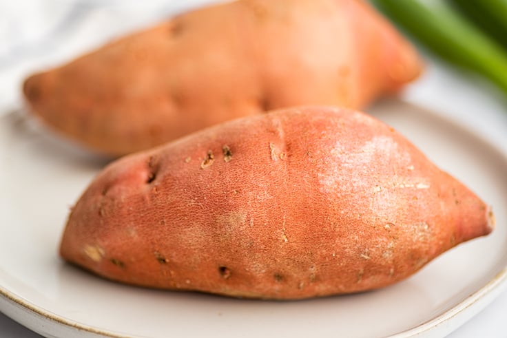 Two medium sweet potatoes on a plate.