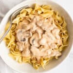 Pork stroganoff over a egg noodles in a bowl.