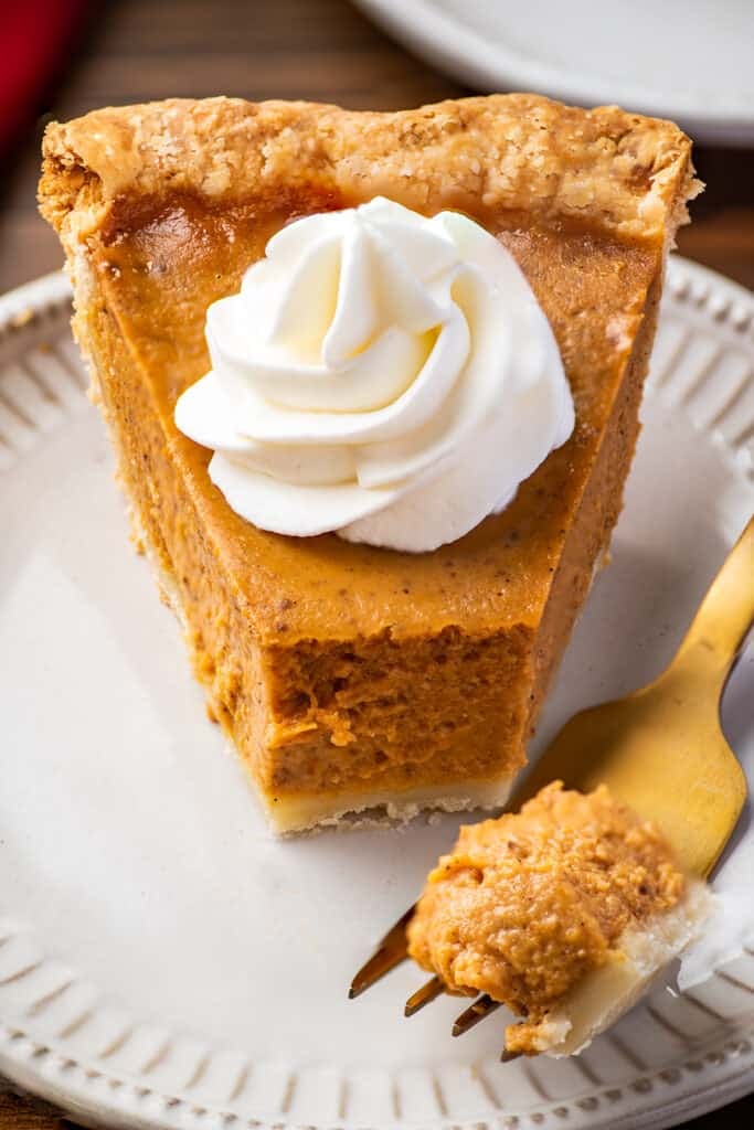 Slice of pumpkin pie with a forkful removed.