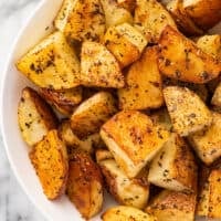 Close up of Italian roasted potatoes in a white bowl.