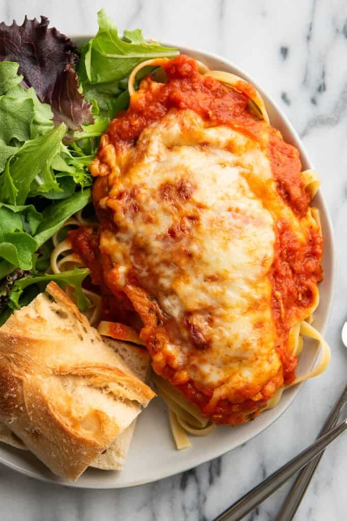 A chicken breast with mozzarella baked on top on a plate