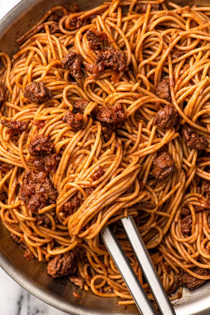 close up shot of a bolognese with some bolognese wrapped around tongs