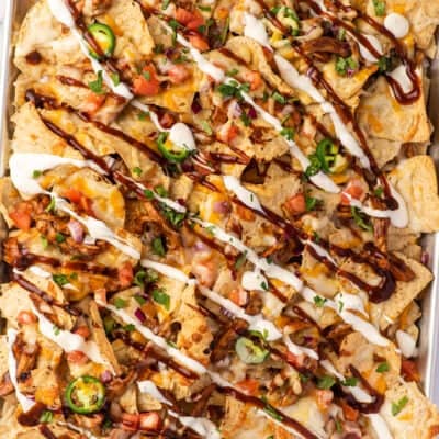 BBQ chicken nachos with ranch and bbq sauce drizzled on.