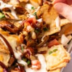 BBQ chicken nachos being picked up from a sheet pan.