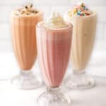 Strawberry, vanilla, and chocolate milkshake recipes in clear glasses.