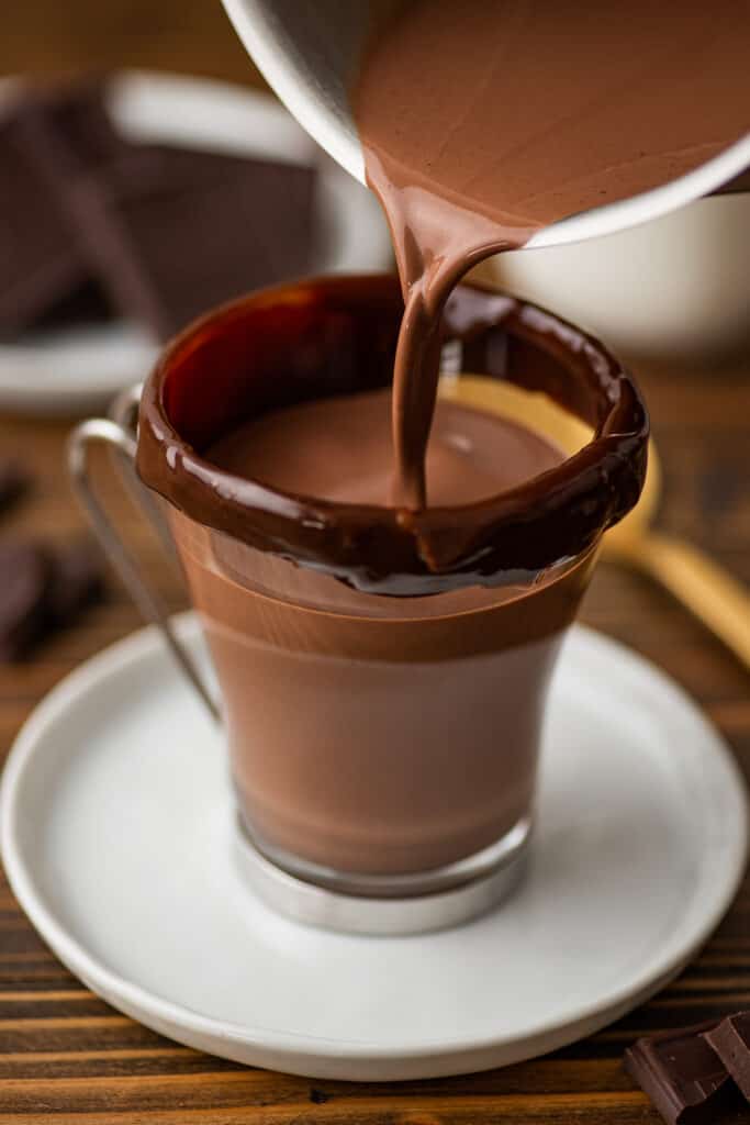 Hot chocolate being poured into a glass mug.