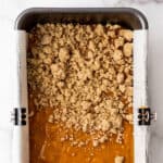 Streusel topping being added to pumpkin bread batter.